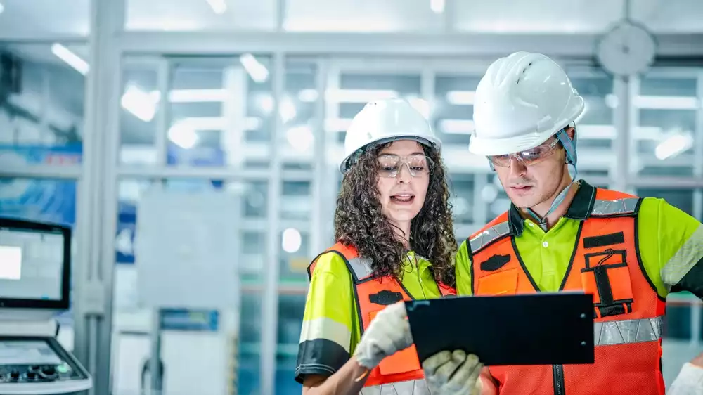Two engineers reviewing a tablet in a factory,